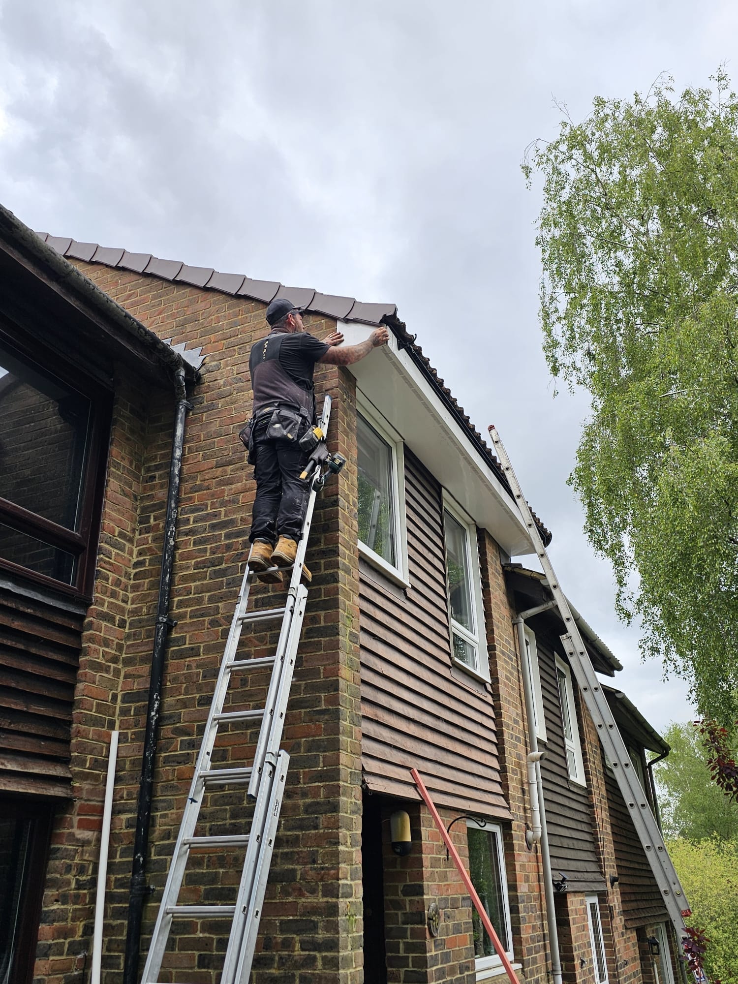 Remastered Roofing installer fitting new uPVC fascia from ladder