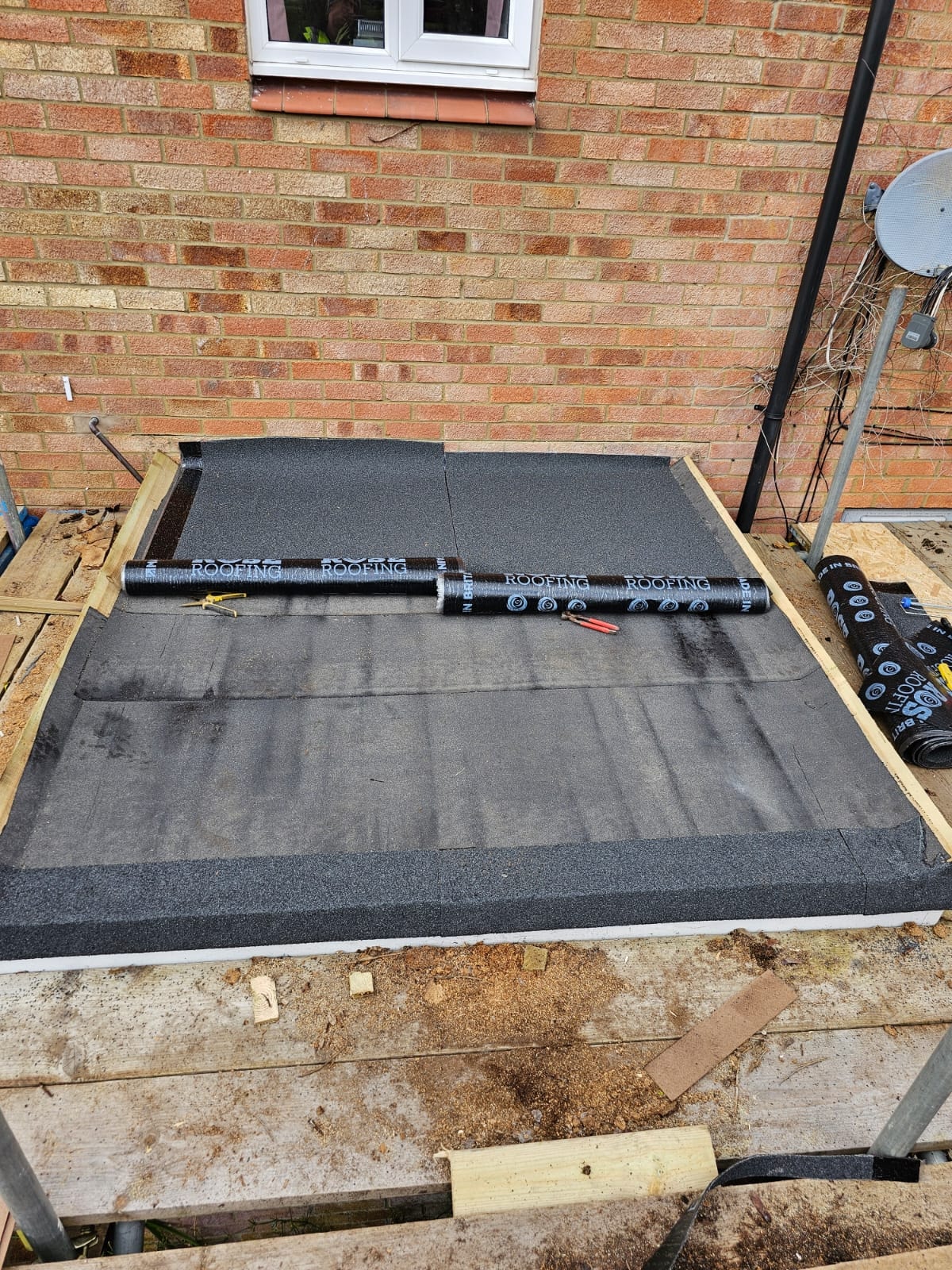 Cap sheet being laid on new flat roof